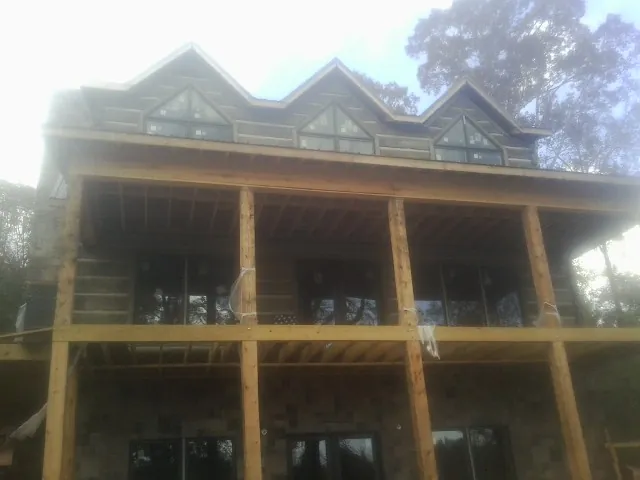 Dormers and porch framing on a large log home under construction — Roof Coating work by our crew in Citra