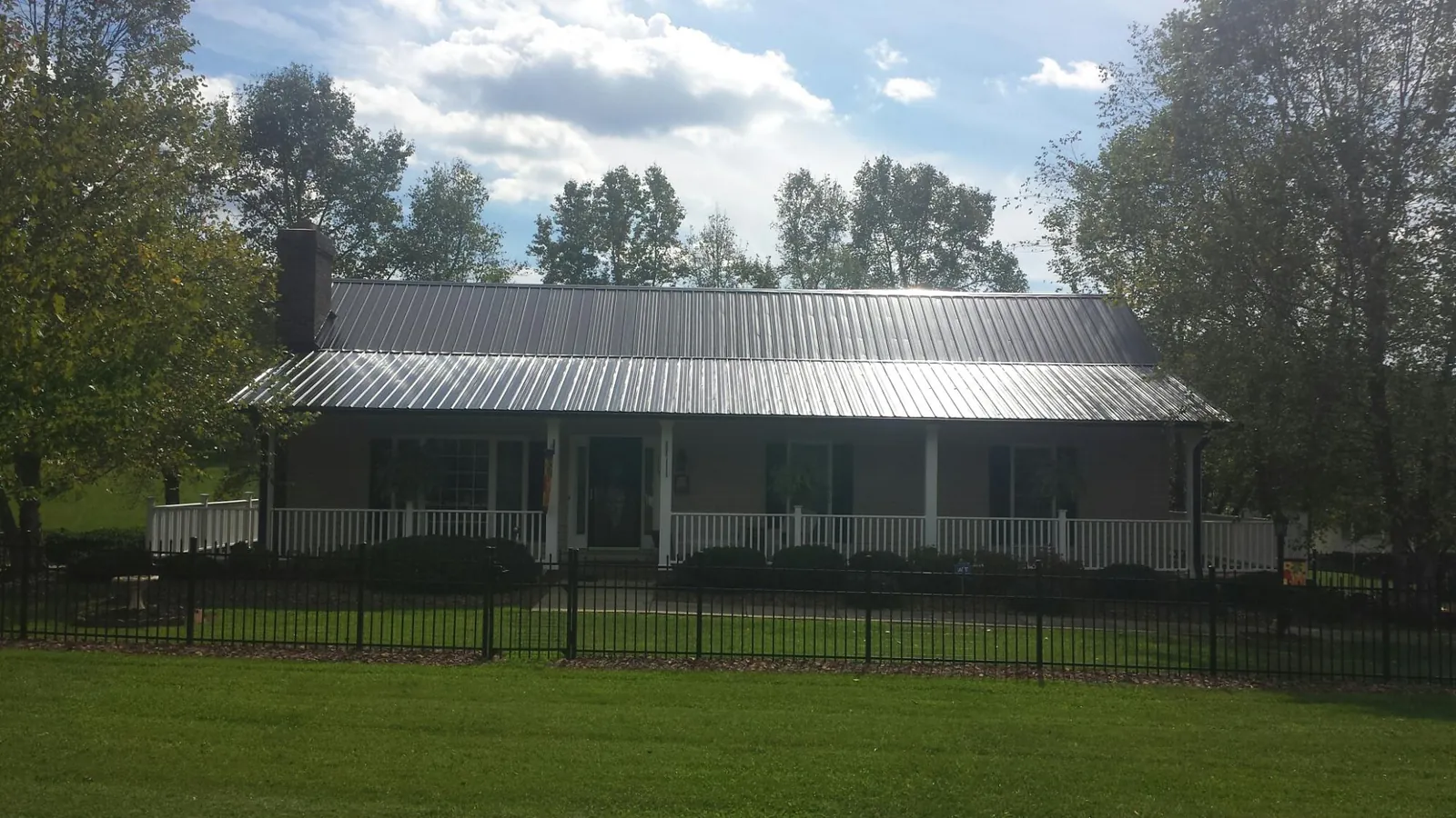 Gray metal roof on a brick ranch with a full width front porch — Gutter Guard Installation work by our crew in Citra