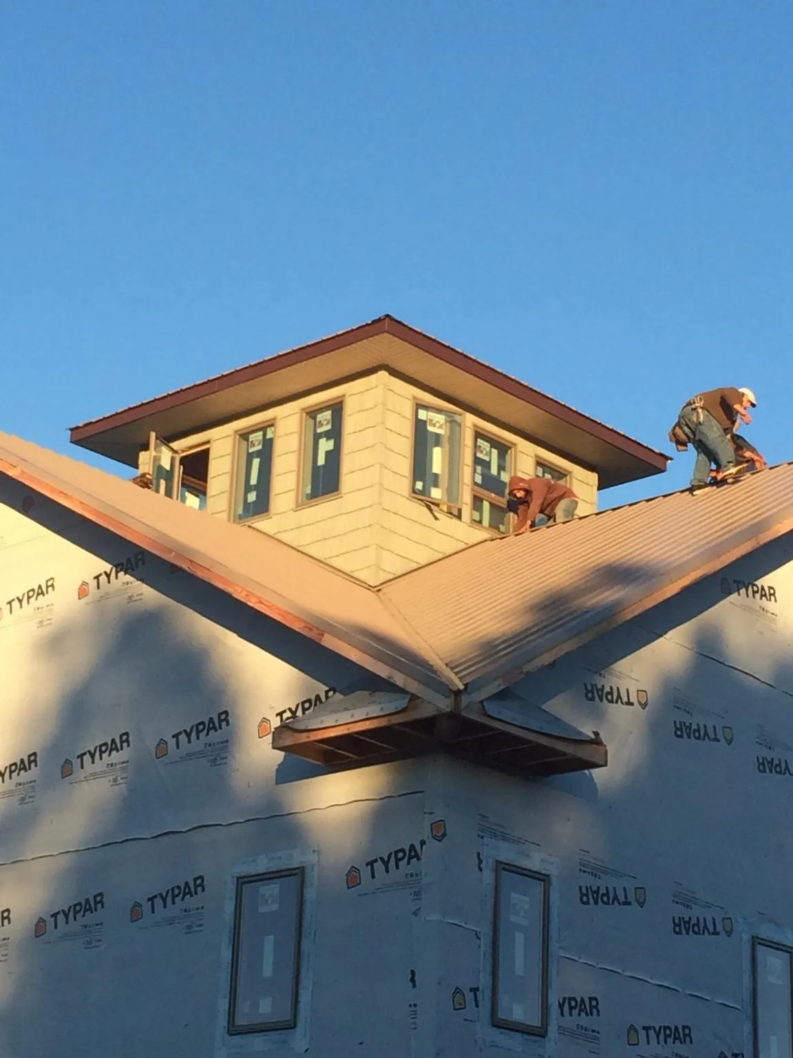Roofers working around a rooftop cupola on a new metal roof at sunset — Roof Waterproofing in Citra by Roofing Brothers